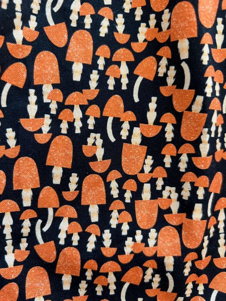 Black cotton a-line dress with pockets featuring a retro 60s orange and white mushroom print on fabric