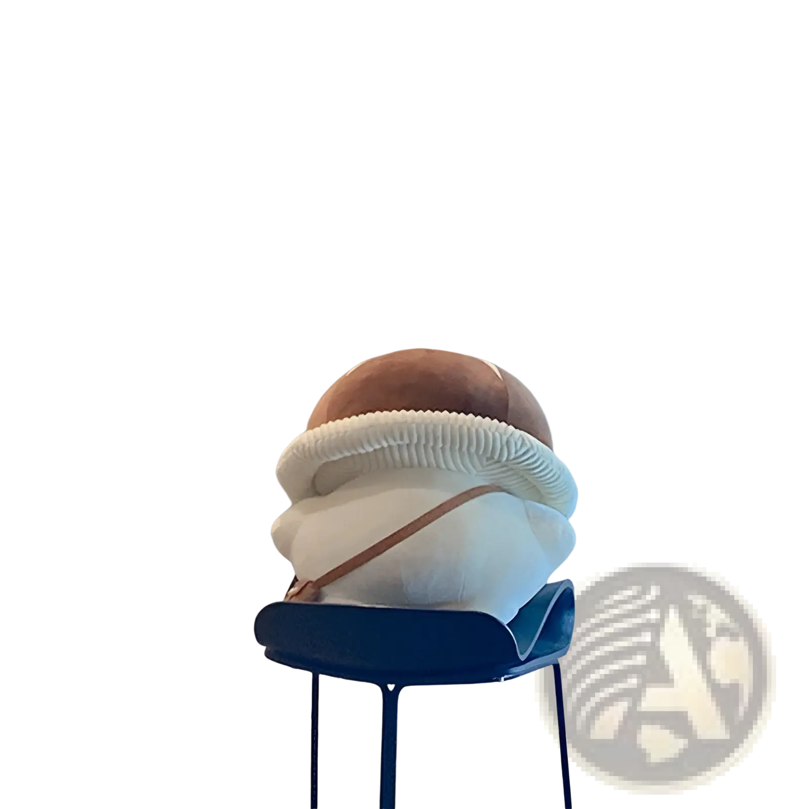 A plush brown and white corduroy bread-shaped mushroom pillow with a ribbed edge on a blue bar stool