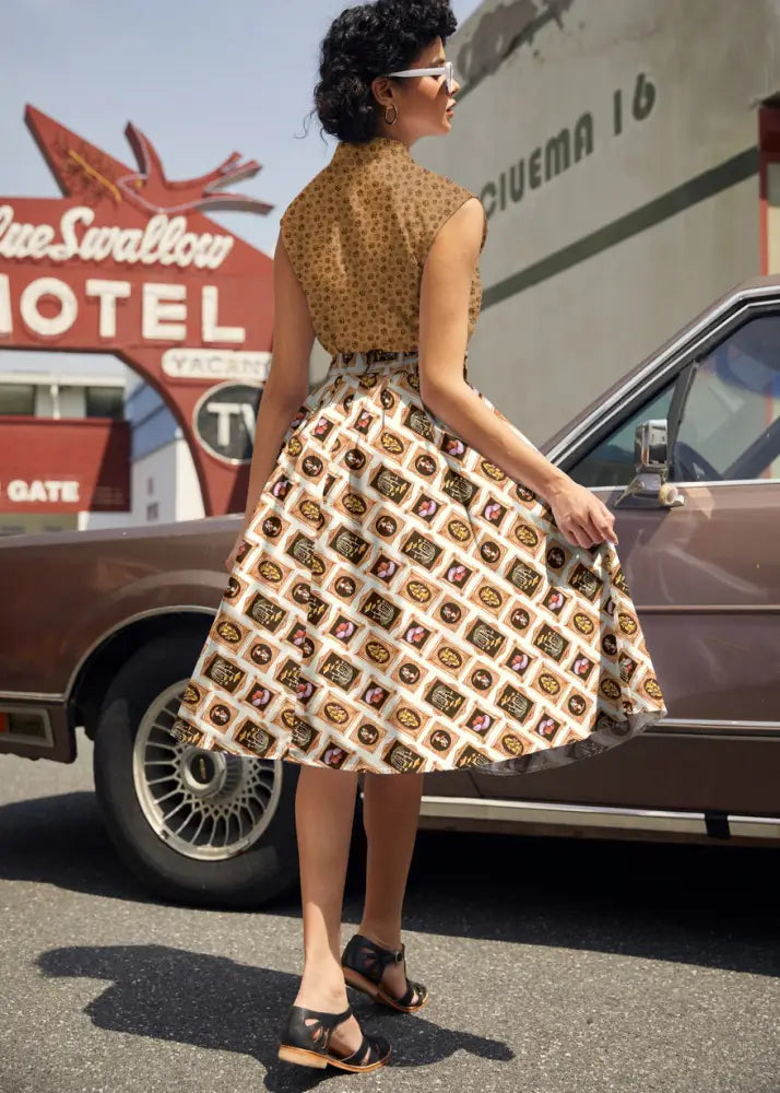 A woman wears a vintage mushroom portrait print Doris flared cotton skirt in brown and cream geometric pattern