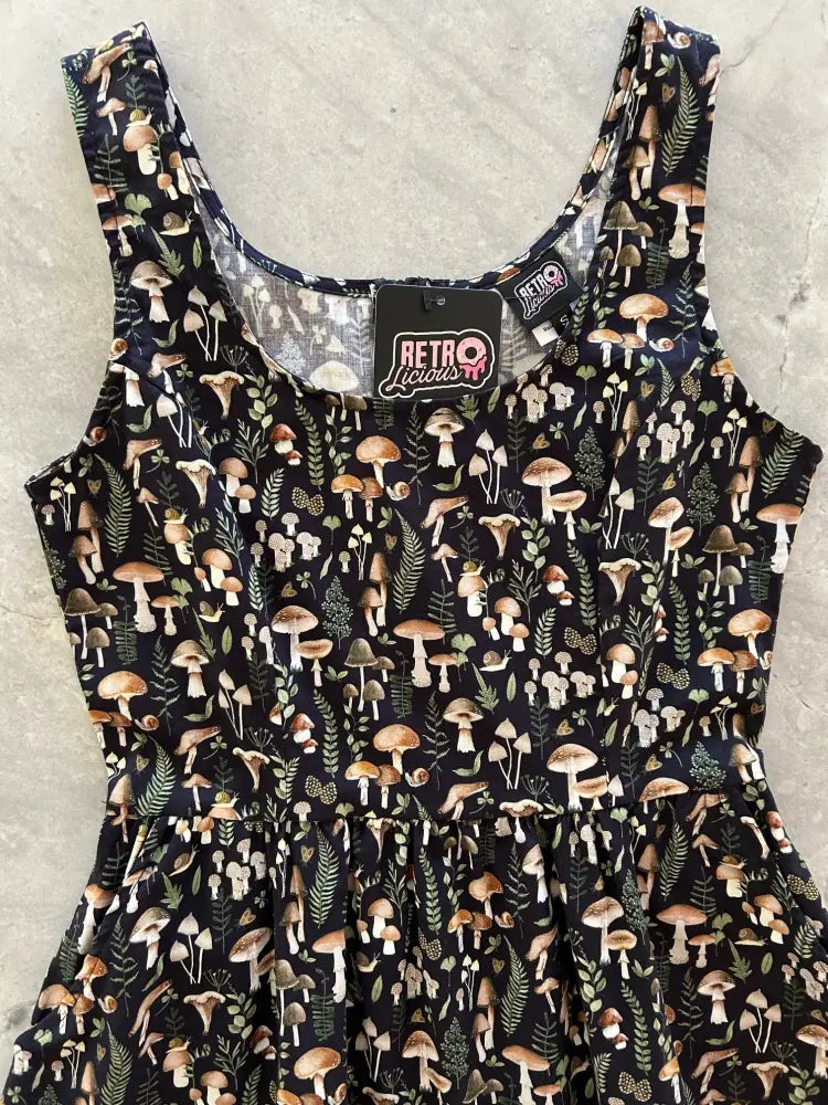 A black sleeveless cotton fit and flare dress with brown and beige vintage mushroom print and green foliage by Retro Liquids