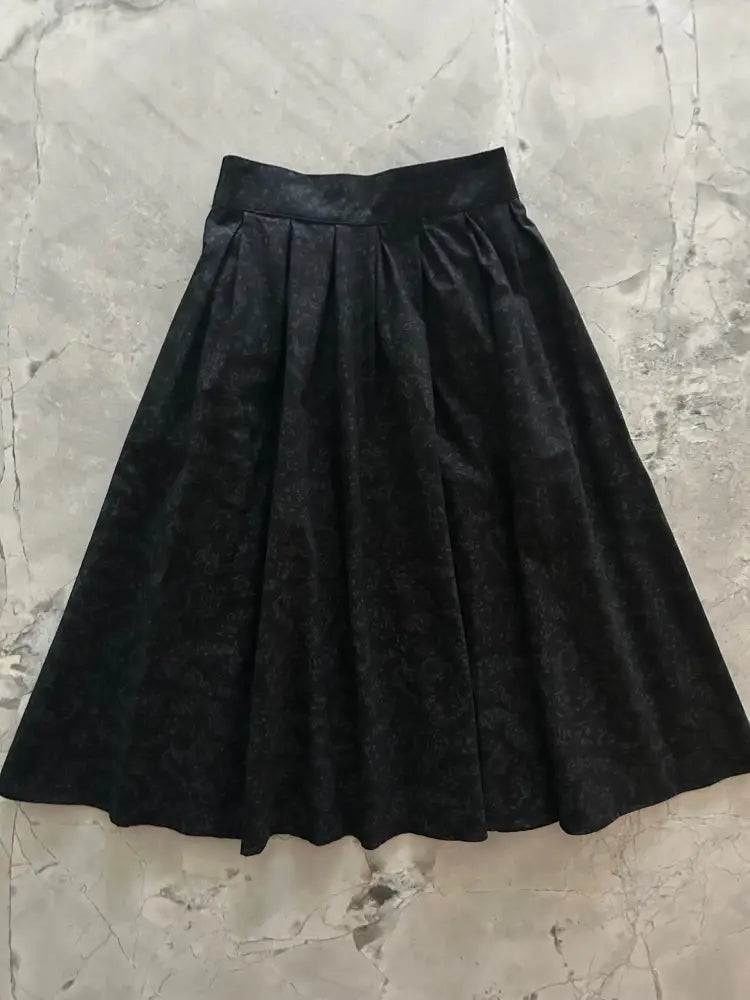 Black high waisted pleated cotton a-line skirt with subtle textured pattern and smooth waistband for elegant wear