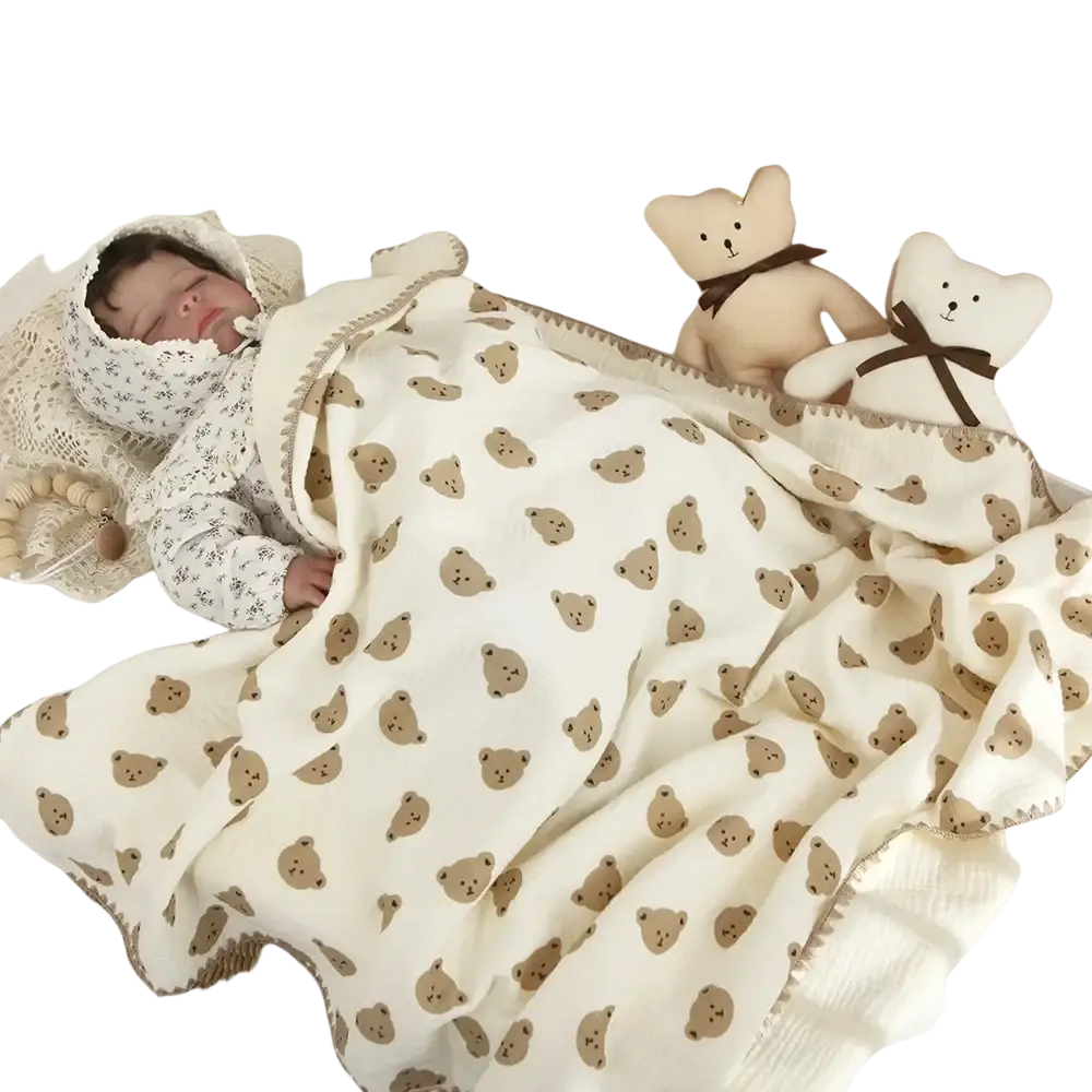 Cream-colored muslin cotton baby swaddle blanket with brown teddy bear faces soft fabric and decorative stitching edges