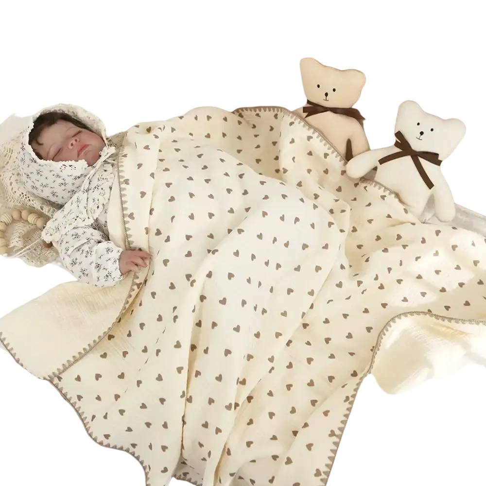 Cream-colored muslin cotton baby swaddle blanket with brown heart pattern and soft textured edge