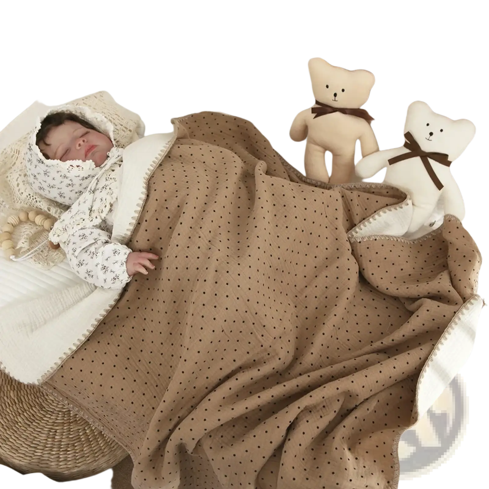 Muslin cotton baby swaddle blanket in beige with black polka dots and white border draped over a sleeping baby in a crib