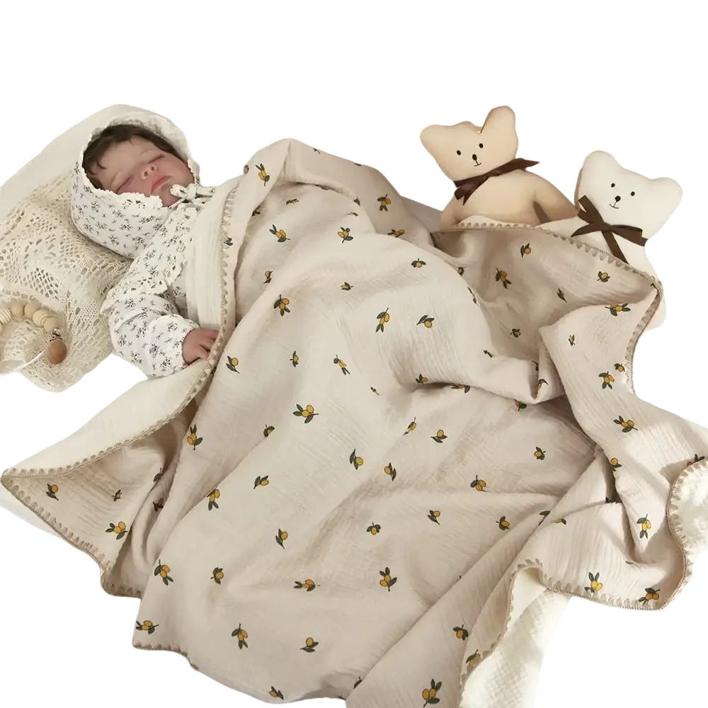 Muslin cotton baby swaddle blanket in soft cream with yellow citrus fruit pattern and green stems, with woven trim