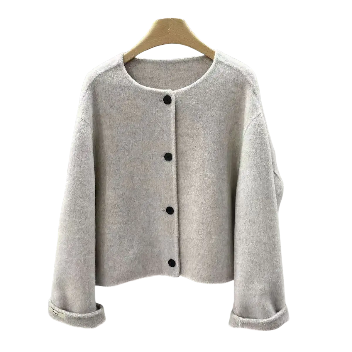 A soft light gray knit cardigan with black buttons and rolled cuffs for women complementing a mustard yellow wool blend short coat