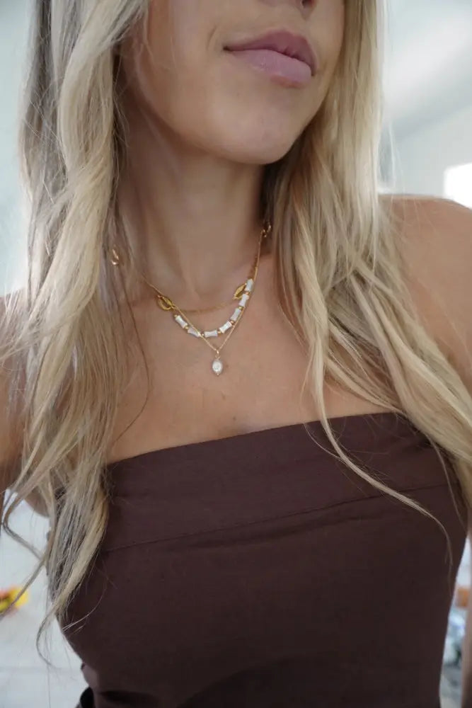 Mykonos white ceramic and gold beaded chain necklace with gold-toned layered delicate chain, cylindrical beads, and teardrop pendant