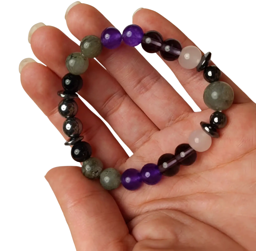 A hand holds a natural amethyst and magnetic stone beaded unisex bracelet with purple black and grayish-green stones