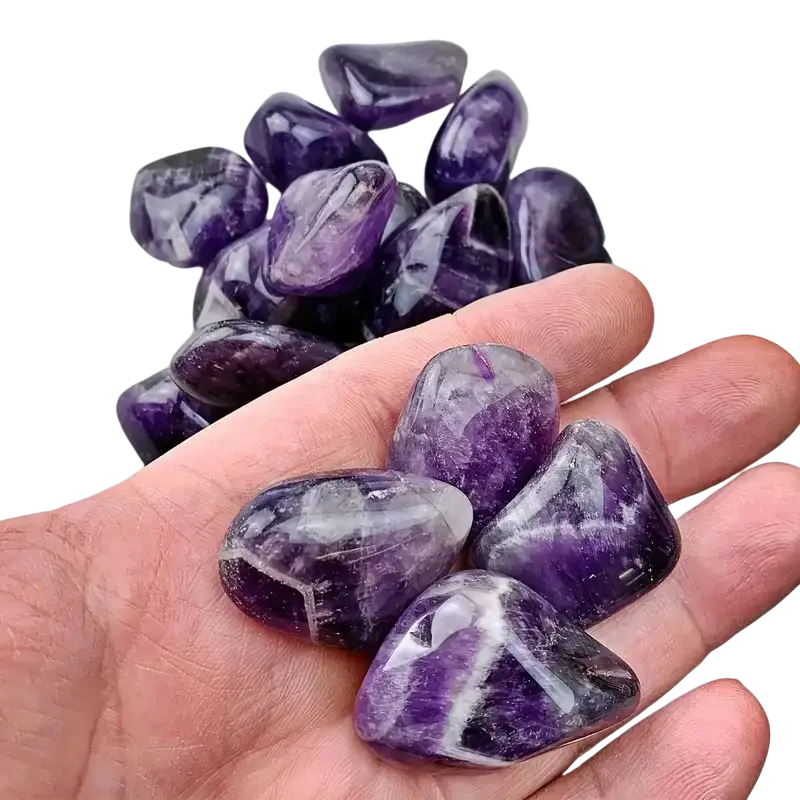 A hand holds natural amethyst tumbled stones with deep purple hues and white veining for reiki healing 100g