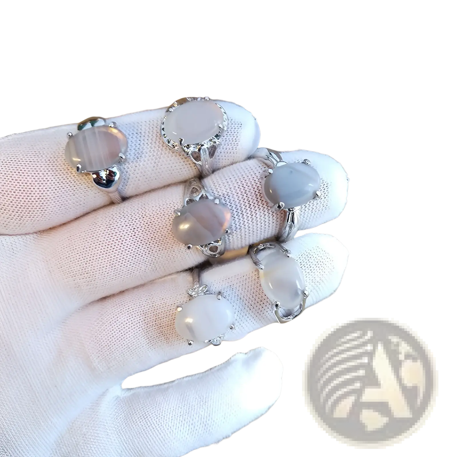 A hand in a white glove displays five silver tone rings with oval moonstone cabochons from a natural gemstone collection