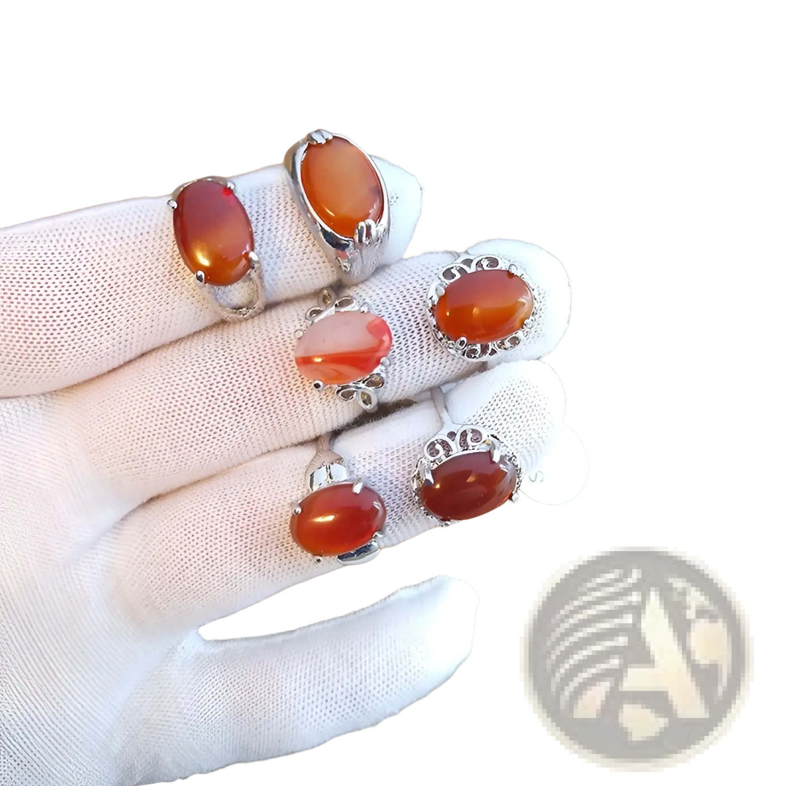 A hand in a white glove displays five oval carnelian rings with silver tone intricate filigree settings