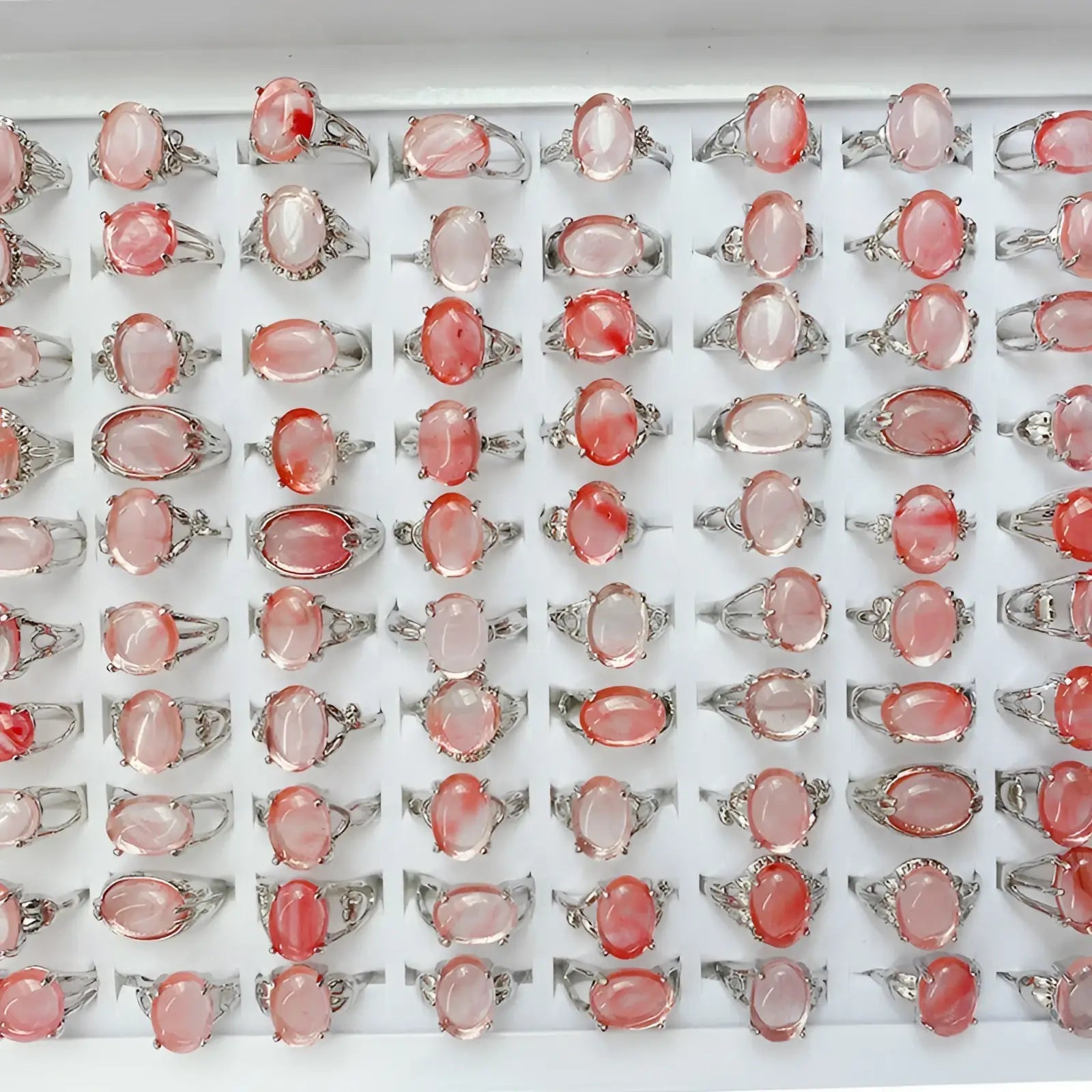 Rows of silver tone statement rings with oval translucent pink and red natural gemstones in ornate metal bands