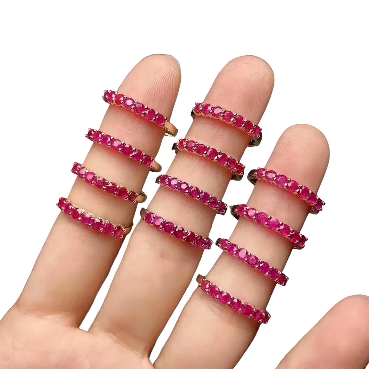 A hand displays multiple delicate rose gold natural ruby silver ring bands with continuous vibrant red rubies