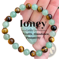 A hand holds a natural tiger eye and green aventurine beaded bracelet with translucent green and golden stones