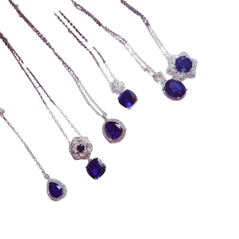 A collection of silver necklace pendants with created sapphire blue gemstone in diamond-encrusted fine jewelry settings