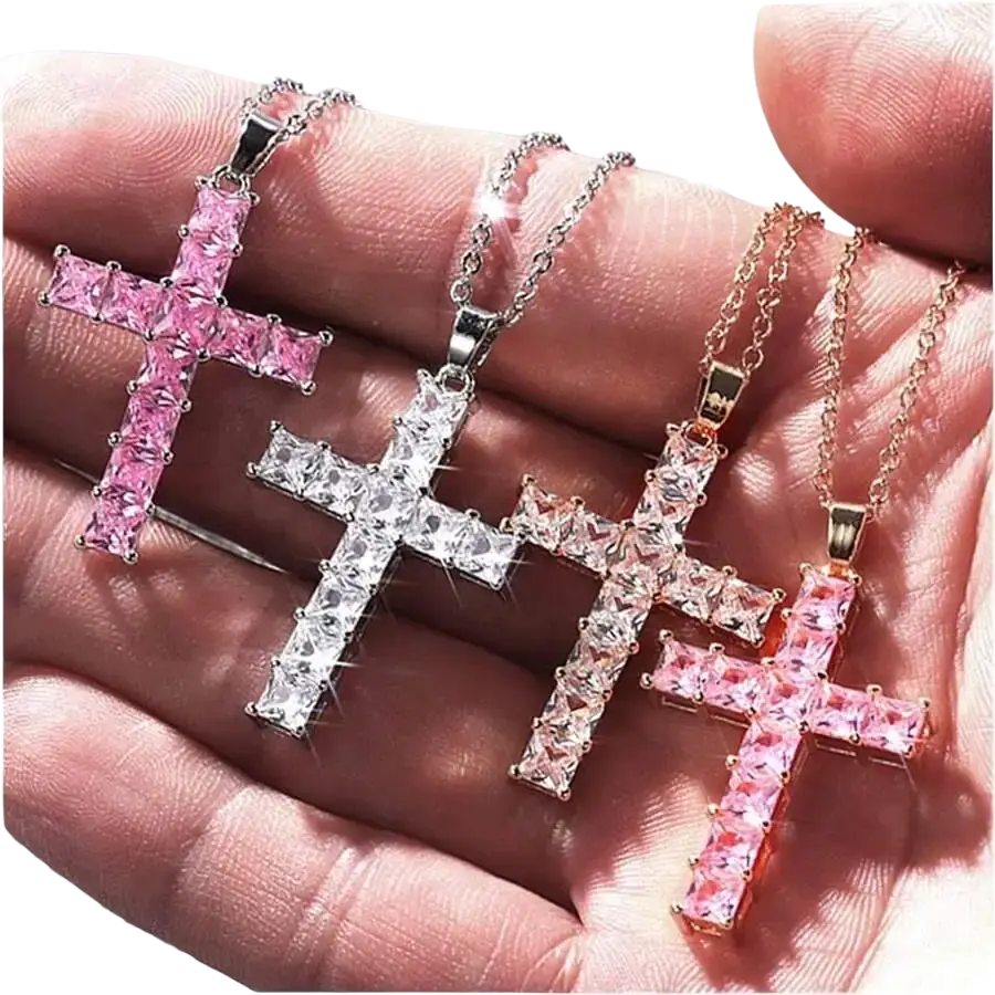 A hand holds three female pendants gold crystal cross necklaces with rectangular pink and clear crystals in silver and rose gold