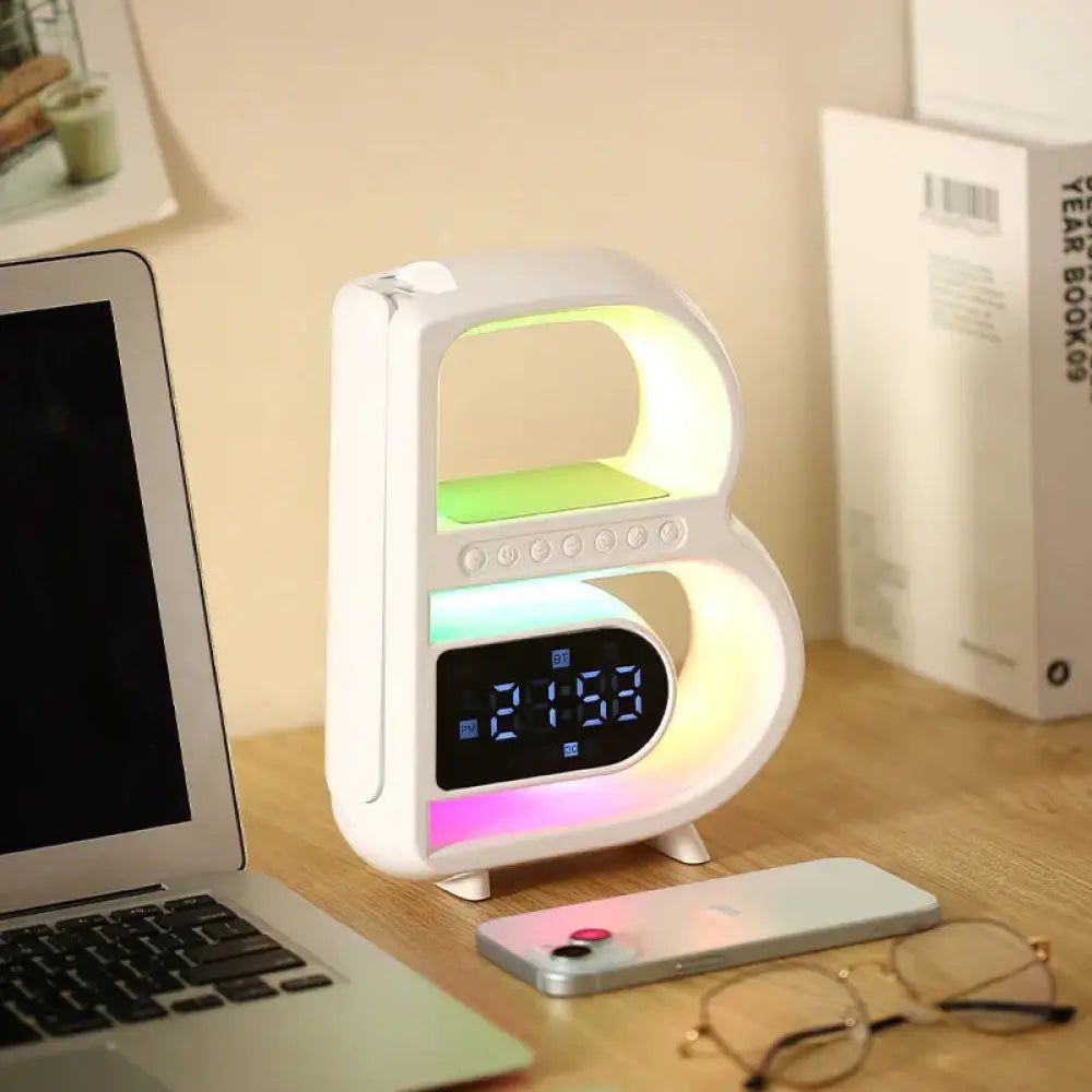 White b-shaped LED clock with glowing interior displaying 2:53 in smart RGB Bluetooth speaker and wireless charger