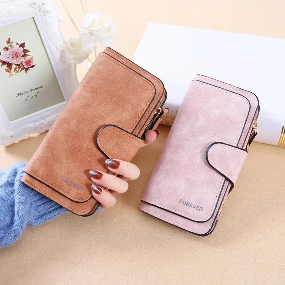 Women’s forever suede trifold buckle wallet in tan and light pink with black stitching and embossed brand name on front