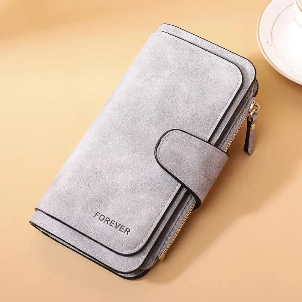 Women’s forever suede trifold buckle wallet in gray suede with black trim gold zipper and embossed forever detail