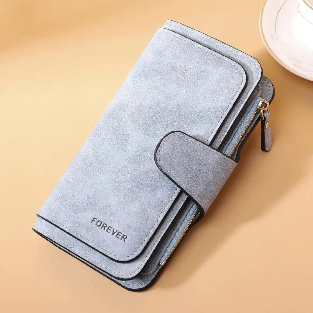 A light gray suede women’s forever trifold buckle wallet with flap closure and gold-tone zipper accents