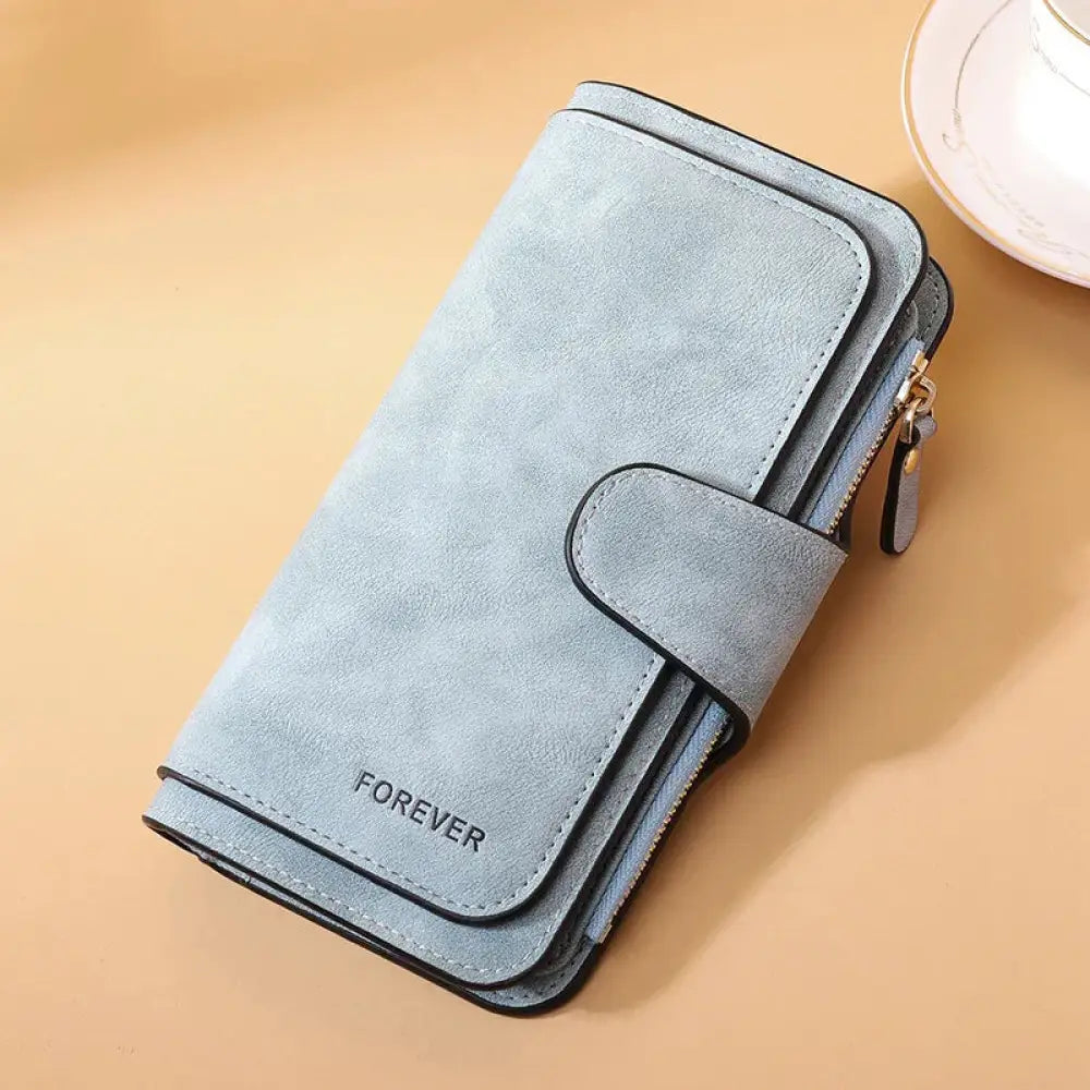 Light blue suede women’s forever trifold buckle wallet with black stitching and gold-toned zipper detailing