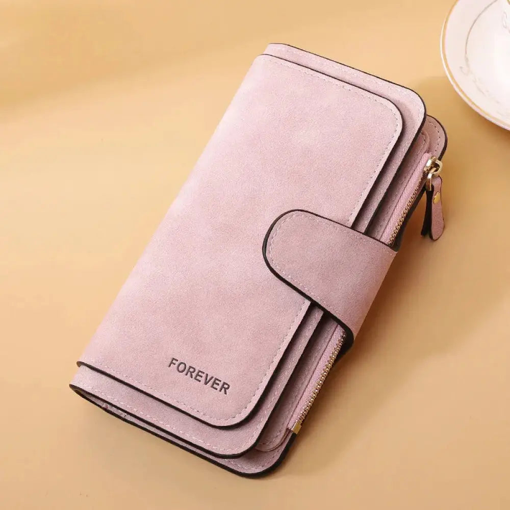 A soft pink suede womens forever trifold buckle wallet with flap closure, gold-tone zipper, and embossed lettering