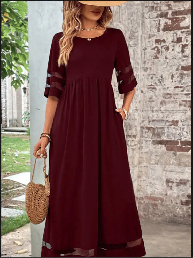 A maroon mesh patchwork maxi dress with sheer accents three-quarter sleeves flared skirt and pockets