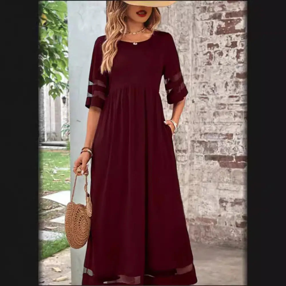 A flowing maroon mesh patchwork maxi dress with three-quarter sleeves sheer panels and relaxed flared silhouette