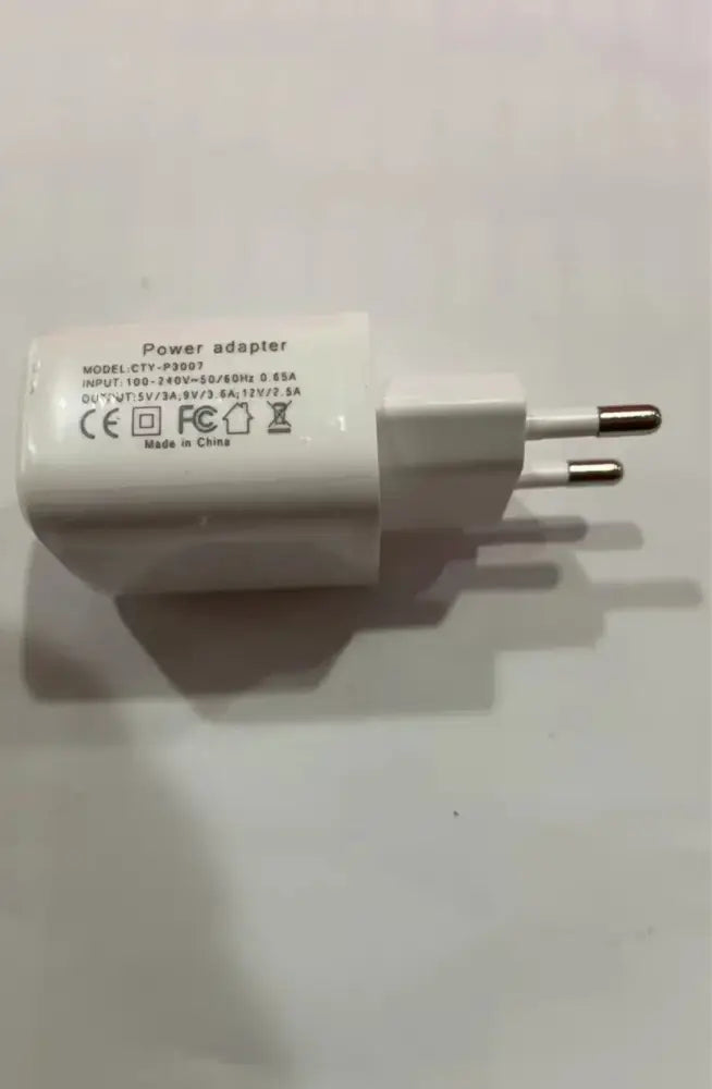 White plastic power adapter with two metallic prongs showing printed specifications for g-shaped led lamp with bluetooth speaker and wireless charger