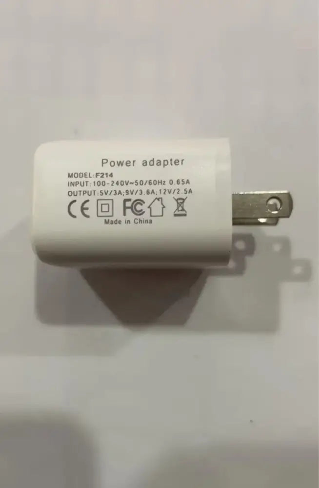 White plastic power adapter with metallic plug and printed specifications for g-shaped led lamp with bluetooth speaker and wireless charger