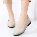Beige leather flat shoes with scalloped toe design and black rubber soles featuring soft cushioned support