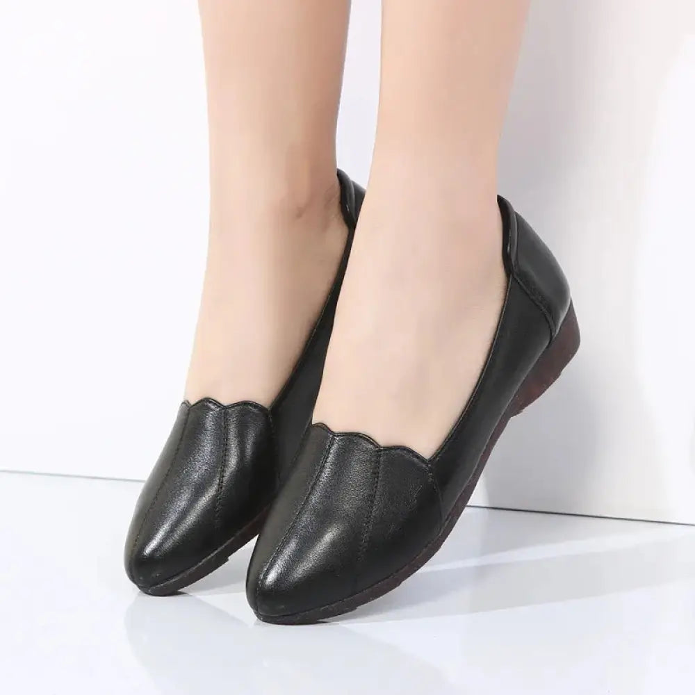 Black leather loafers with scalloped toe design and low heel featuring soft cushioned soles for comfortable wear