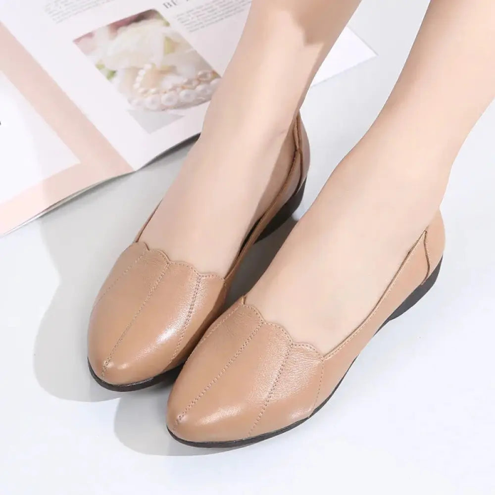 Beige leather loafers with scalloped toe design and black rubber soles in soft cushioned flats style