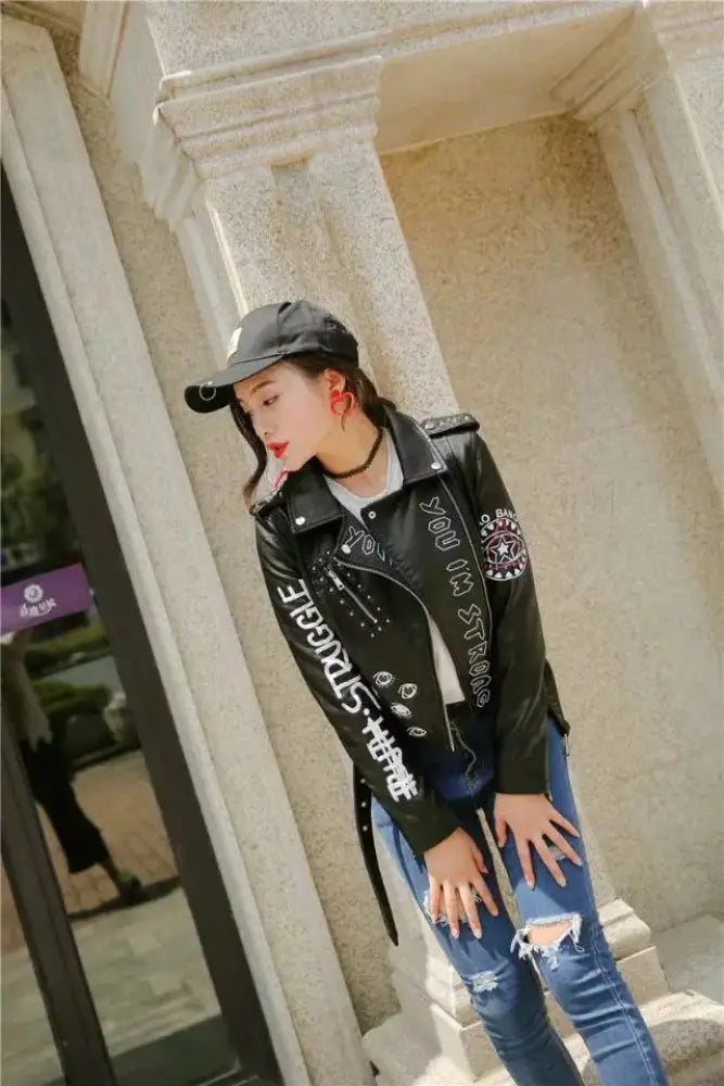 Black faux leather biker jacket with white studded lettering and eye embroidered patches on the back side