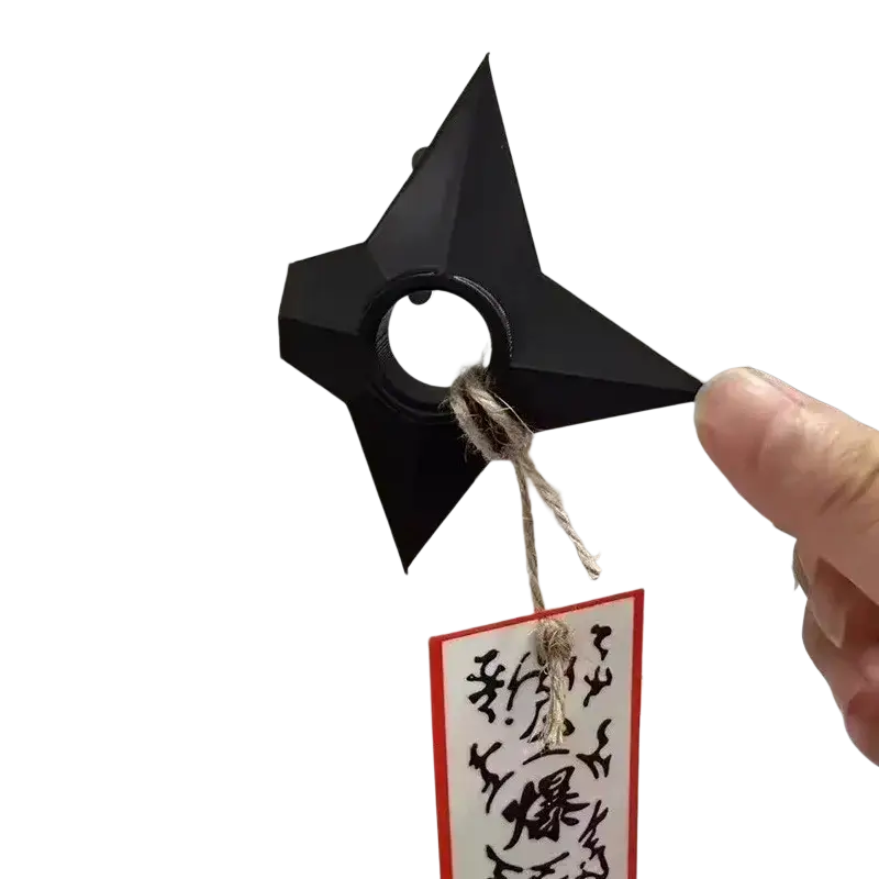 Black pvc ninja kunai fridge magnet shuriken toy with central ring and attached twine tag displayed against white background