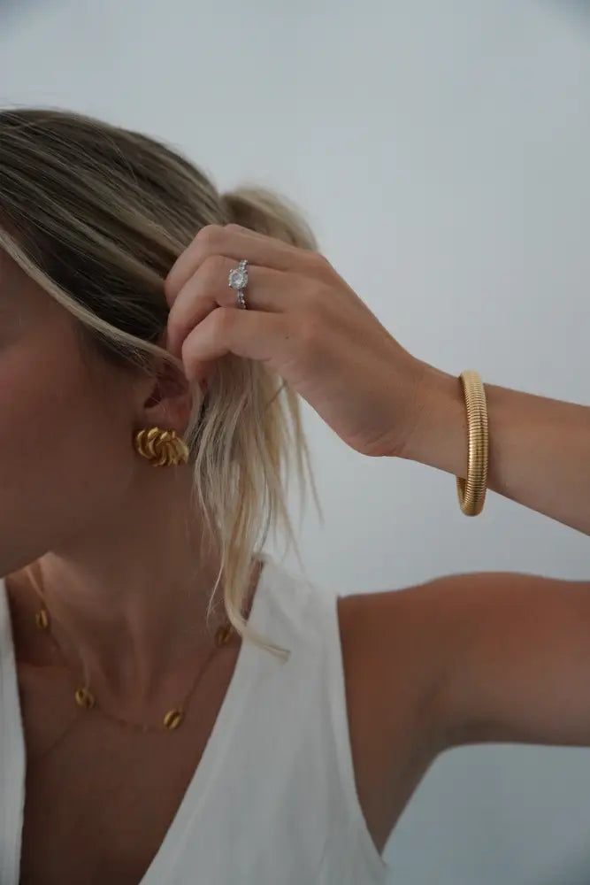 Gold-toned twisted knot earrings complementing the nova gold ribbed stackable snake bangle bracelet