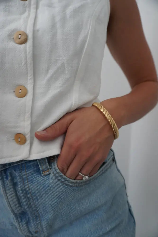 Gold-toned braided nova gold ribbed stackable snake bangle bracelet worn on a wrist showcasing its texture and design