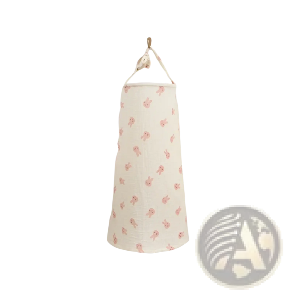 A cream cotton laundry hamper with pink bunny pattern hanging on wall paired with a breathable nursing cover dinosaur print