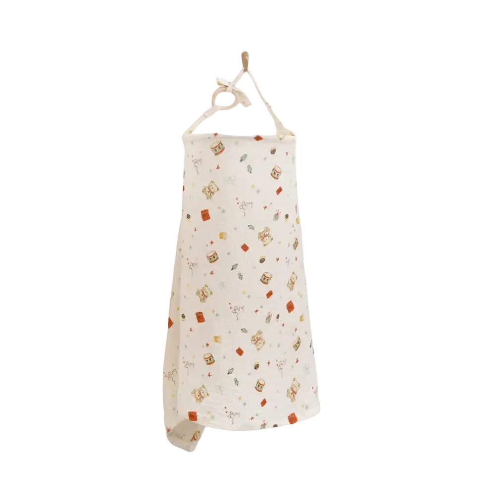 A soft off-white cotton nursing cover with breathable fabric and playful dinosaur print hanging from a wooden hook