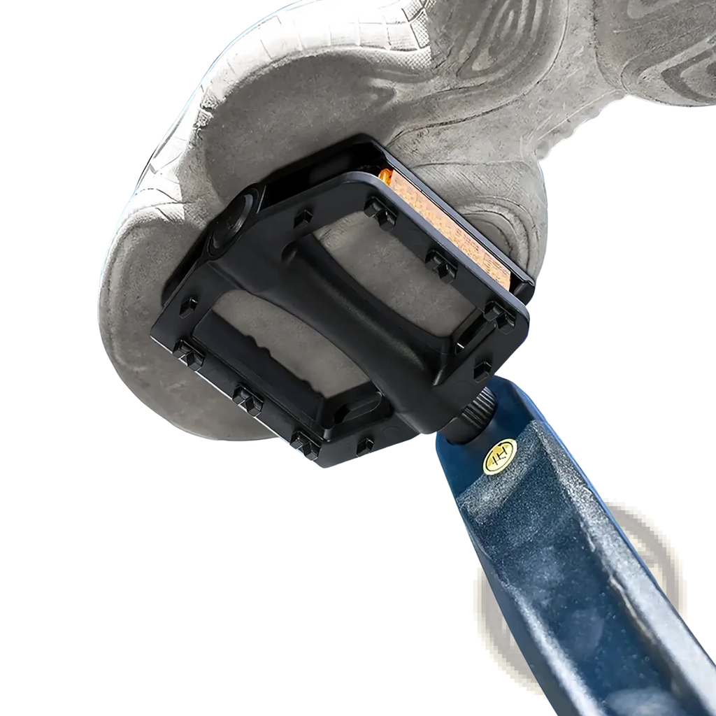 Black nylon mountain bike pedal with textured surface and orange reflector insert attached to bike frame