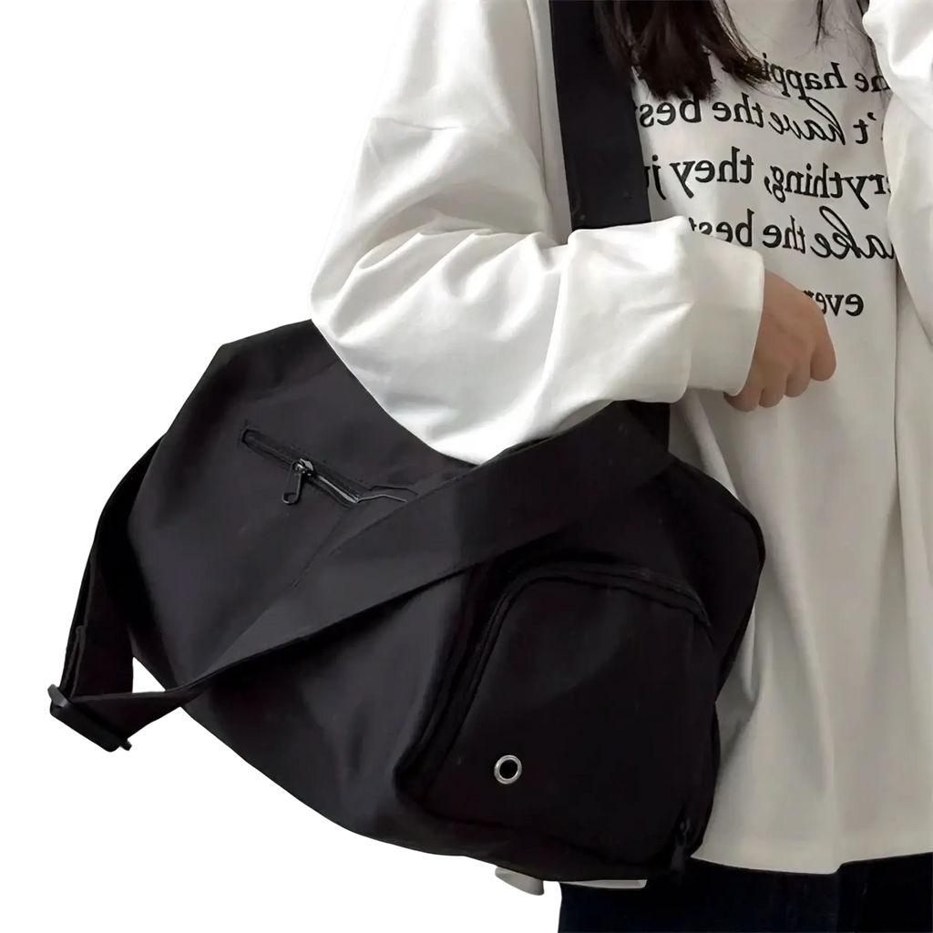 Black nylon travel tote bag with front zippered pocket and circular metal eyelet for casual shoulder use