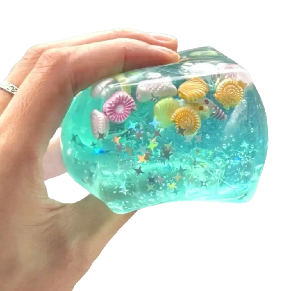 Ocean sensory fidget cube in translucent turquoise filled with seashell charms and star confetti thoughtful gift
