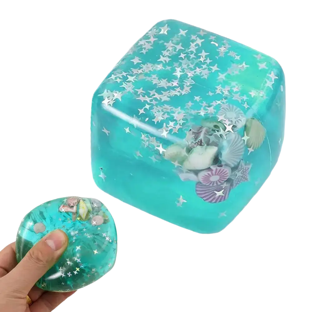 A translucent turquoise cube-shaped ocean sensory fidget cube filled with silver stars and seashells thoughtful gift