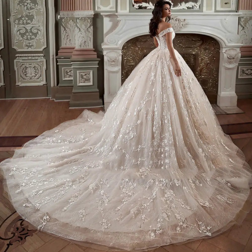 An off-the-shoulder ivory French Mori embroidered wedding dress with floral lace appliqués and a voluminous tulle skirt