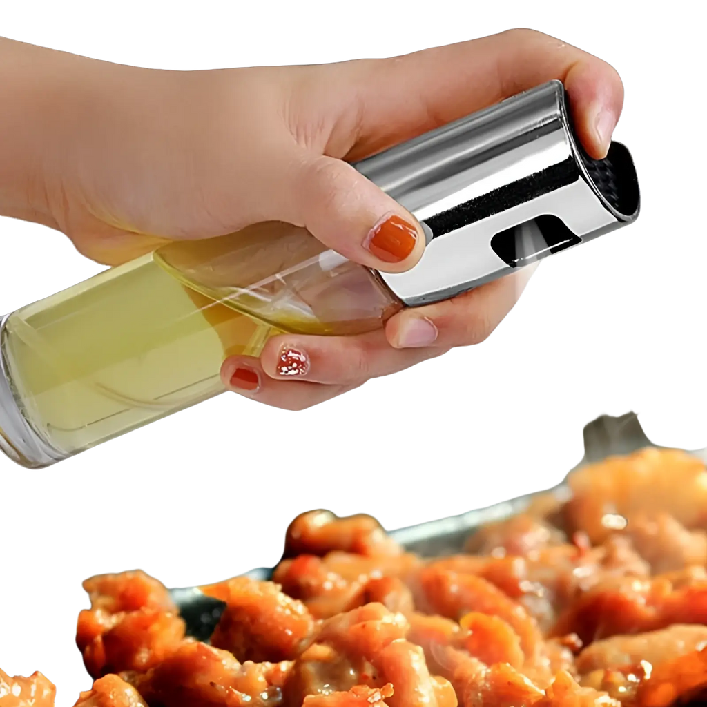 A sleek transparent glass oil spray bottle for cooking with a shiny chrome leakproof nozzle and trigger mechanism