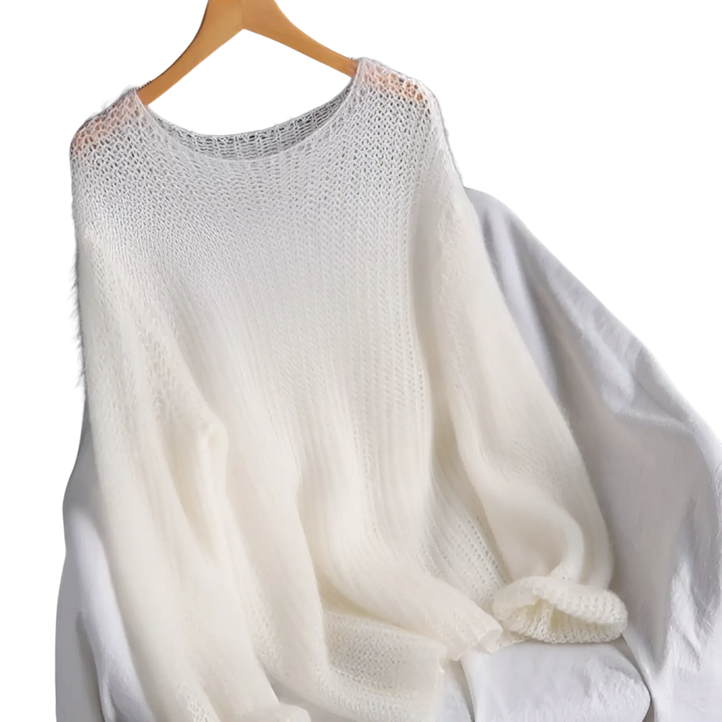 A soft off-white mohair open-knit pullover blouse style knit top with a loose oversized fit on a wooden hanger