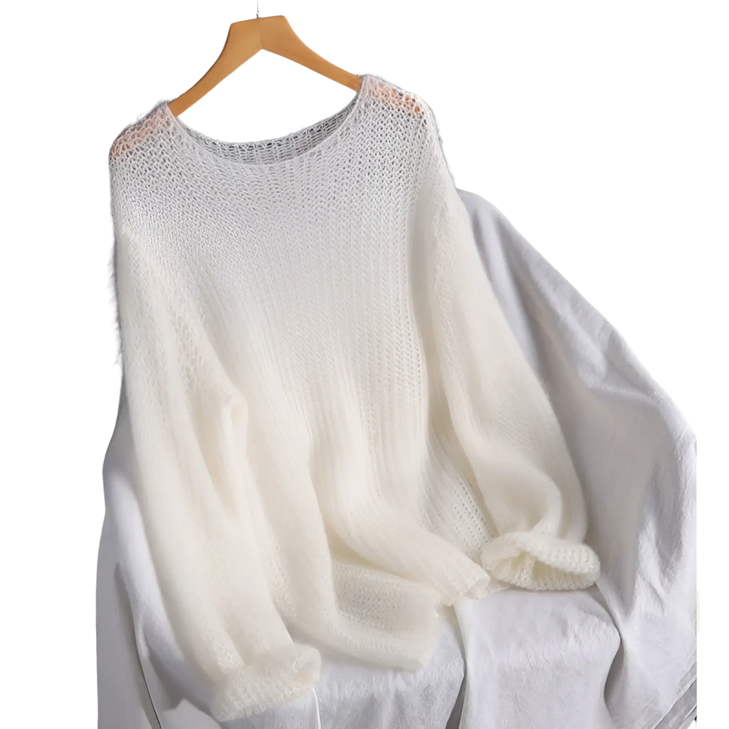 Open knit pullover blouse style knit top in soft off white with loose airy texture and ribbed cuffs on wooden hanger