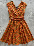 A vibrant orange and yellow plaid cotton dress with v-neckline, cinched waistband, short sleeves, and pockets