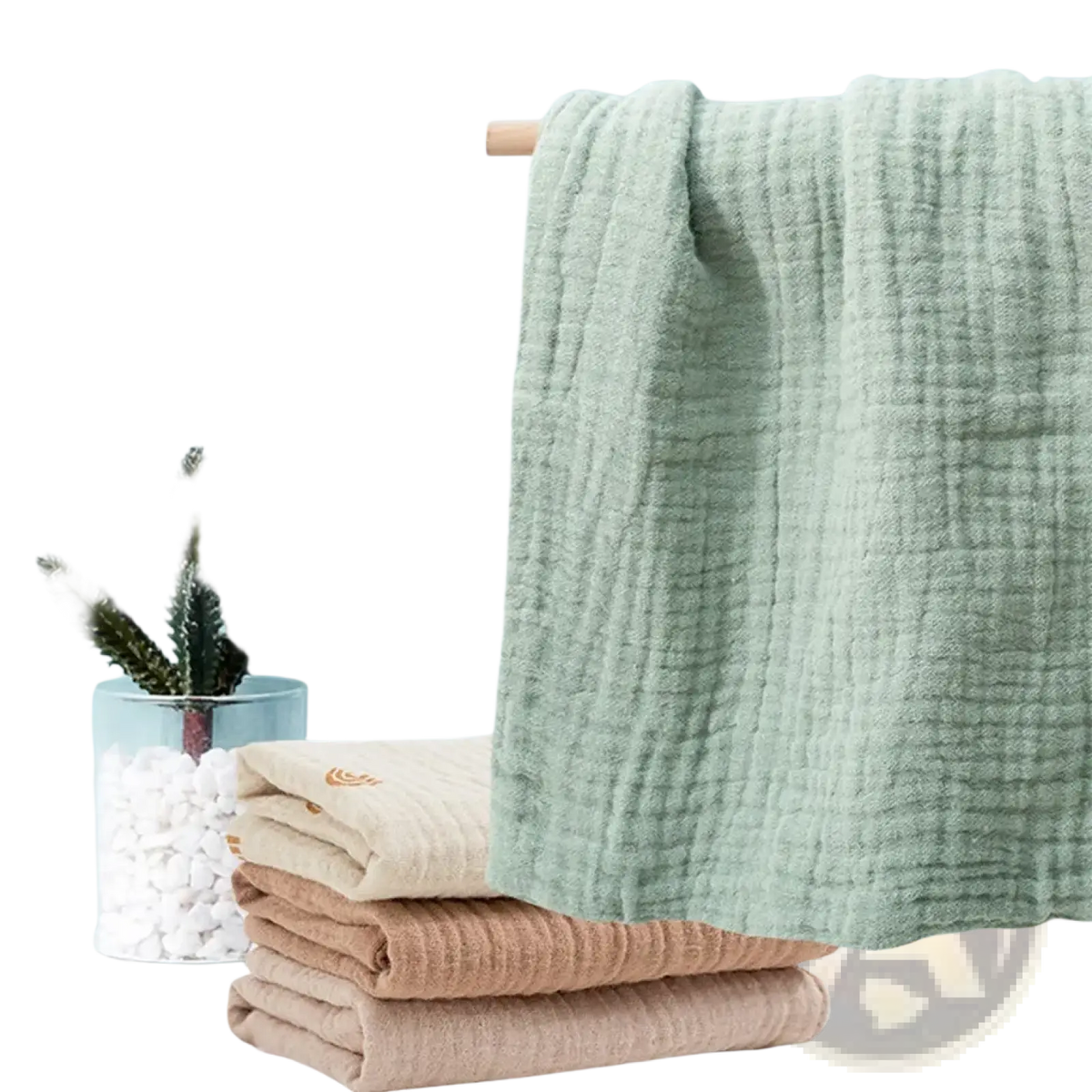 A soft light green organic cotton muslin baby bath towel with subtle grid texture hanging on a wooden rack