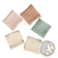 Organic cotton baby bath towel and muslin set in soft pastel colors with subtle ribbed texture and small fabric ties